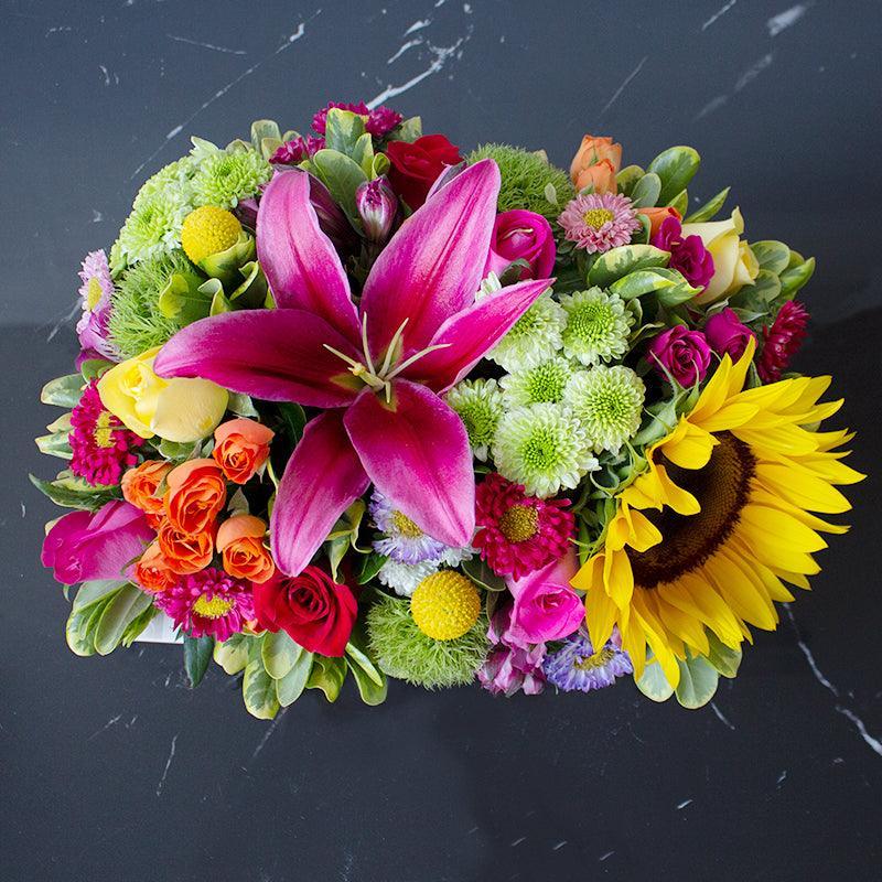 Hermosa canasta especial de mix de Rosas, Mini Rosas, Girasol, Rubina, Mini Rosa, Maxumoto y follajes mixtos. Arreglo floral hecho en una bandeja especial* y colocado en nuestro empaque original de regalo con moño de tela impreso, listo para obsequiar.