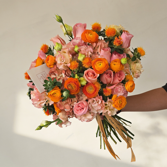 Ramo de flores de ranúnculo naranja, rosas, hortensias pintadas y lisianthus en florero de vidrio