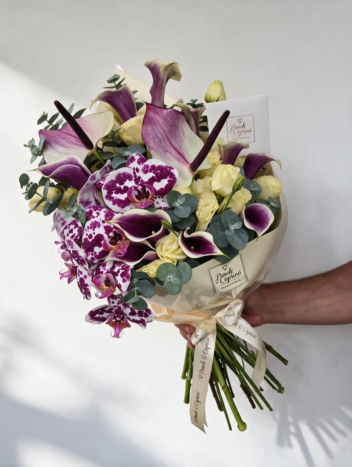 Ramo de flores con calas de agua bicolor, orquídea phalaenopsis vaquita, anturio blanco con morado y lisianthus crema en florero - Ponch & Caprico ALA034