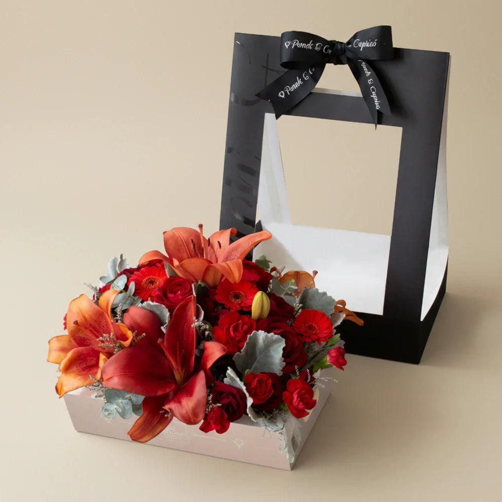 Flores en Caja tipo Canasta de Lillies Rojos, Rosas Rojas, Mini Gerberas Rojas, Clavellinas y Mini Rosas - PCAN001 -