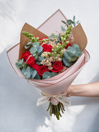 Lindo ramillete atado a mano de Rosas Rojas, Aquilea Melón, Dólar y Dragón Rosa Perrito; envuelto en elegante papel y delicado moño pequeño de tela.  Viene incluido florero de vidrio.