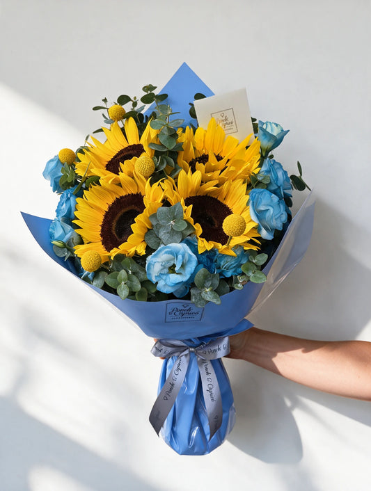 Ramo de Girasoles, Lisianthus tintado a mano en azul, Craspedia y Dólar en envoltura azul - Ponch & Caprico PRAM066