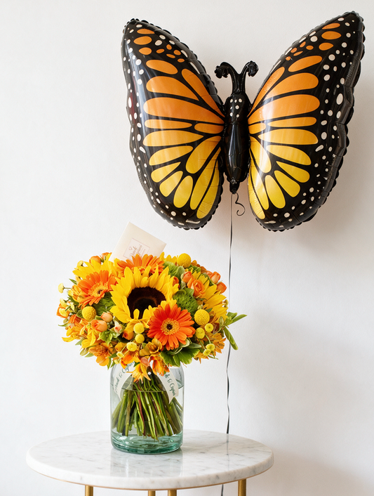 Set de regalo: ramo de gerberas y girasoles en tonos alegres junto a un globo mariposa monarca gigante con helio
