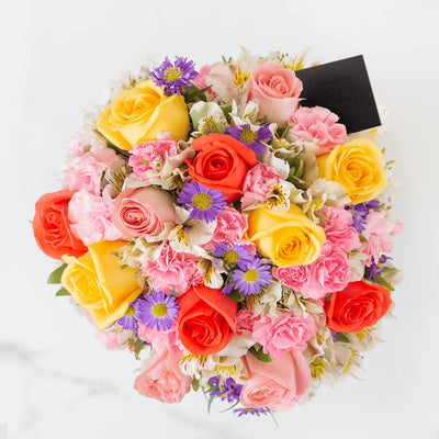 Arreglo de flores frescas elaborado con flores seleccionadas en florero incluido directo en agua. Incluye rosas amarillas, naranjas y hermosas, además de clavellinas rosadas, alstro blanca y montecasino.   Hecho a mano, incluye tarjeta de dedicatoria impresa y listón de tela.