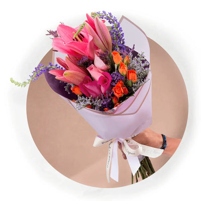 Lindo ramillete atado a mano de Mini Rosas Naranja, Lillies, Rosas Rosada, Rosas Fucsia, Espuma, Verónica y Limonio, envuelto en finos papeles y delicado moño de tela.  Viene incluido florero de vidrio, y caja que cubre el florero (esta última únicamente en la presentación sencilla).