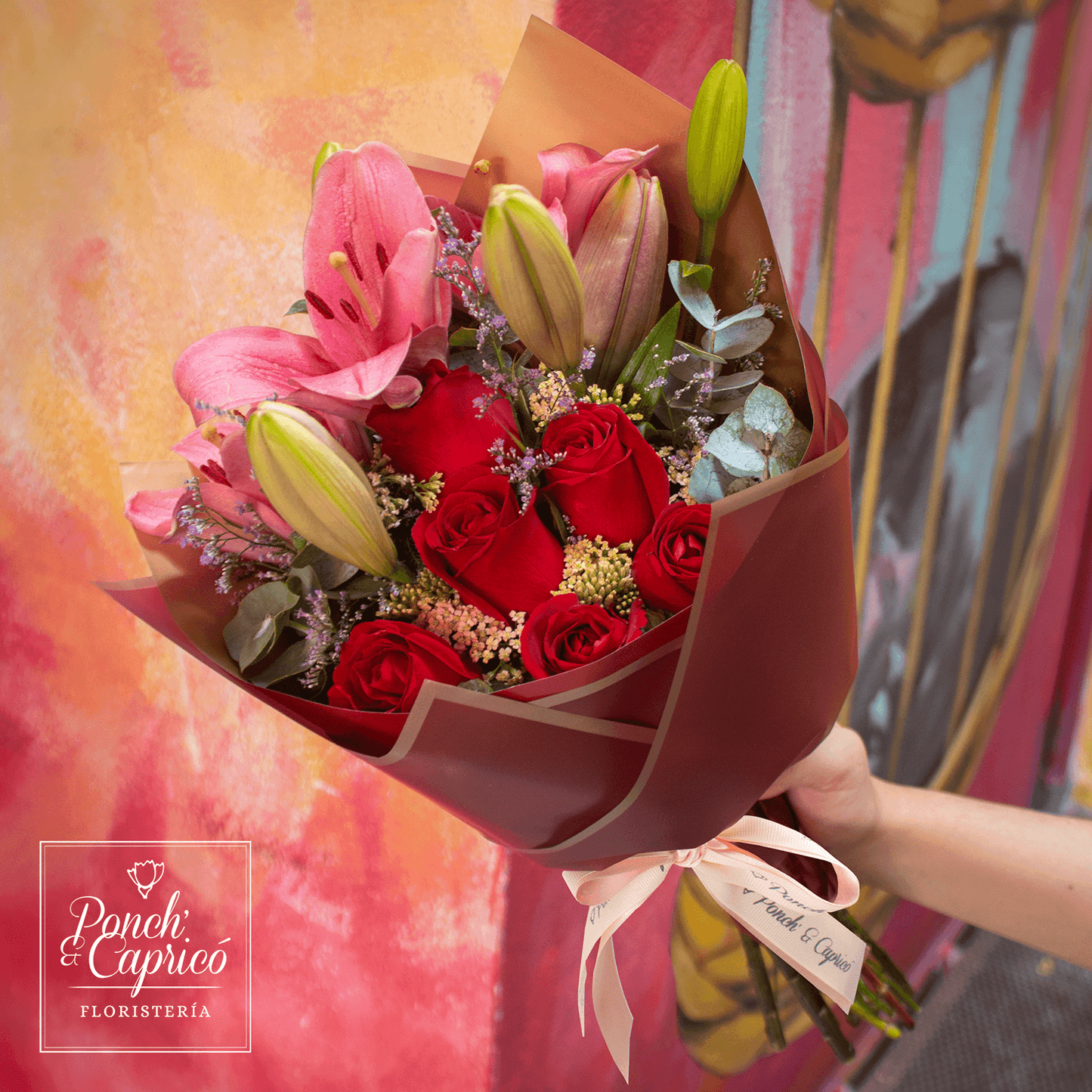 Lindo ramillete atado a mano de Rosas Rojas, Lillies y Aquilea, Limonio y follaje; envuelto en elegante papel y delicado moño pequeño de tela.