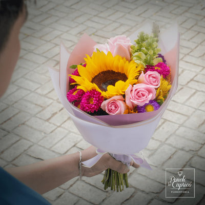 Lindo ramillete atado a mano de Rosa Caricia, Girasol, Astro Amarilla y Dragón Amarillo Perrito, además de Dragón Rosa Perrito y Matsumoto; envuelto en elegante papel y delicado moño pequeño de tela.