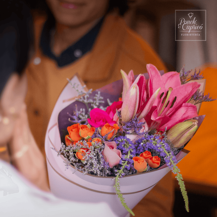 Lindo ramillete atado a mano de Ramillete de Mini Rosa Naranja, Lillies, Rosa Caricia, Rosa Fucsia Topaz, Espuma y Limonio, envuelto en papel elegante y delicado moño pequeño de tela.